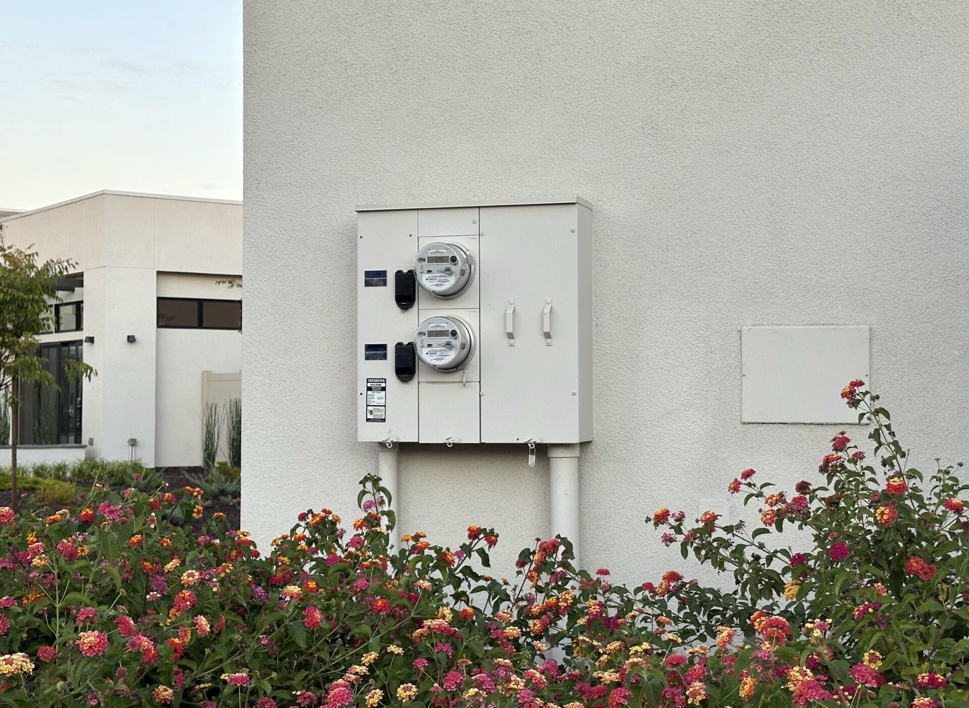Exterior electrical service panel, utility meters, and disconnect switches mounted on a residential wall.